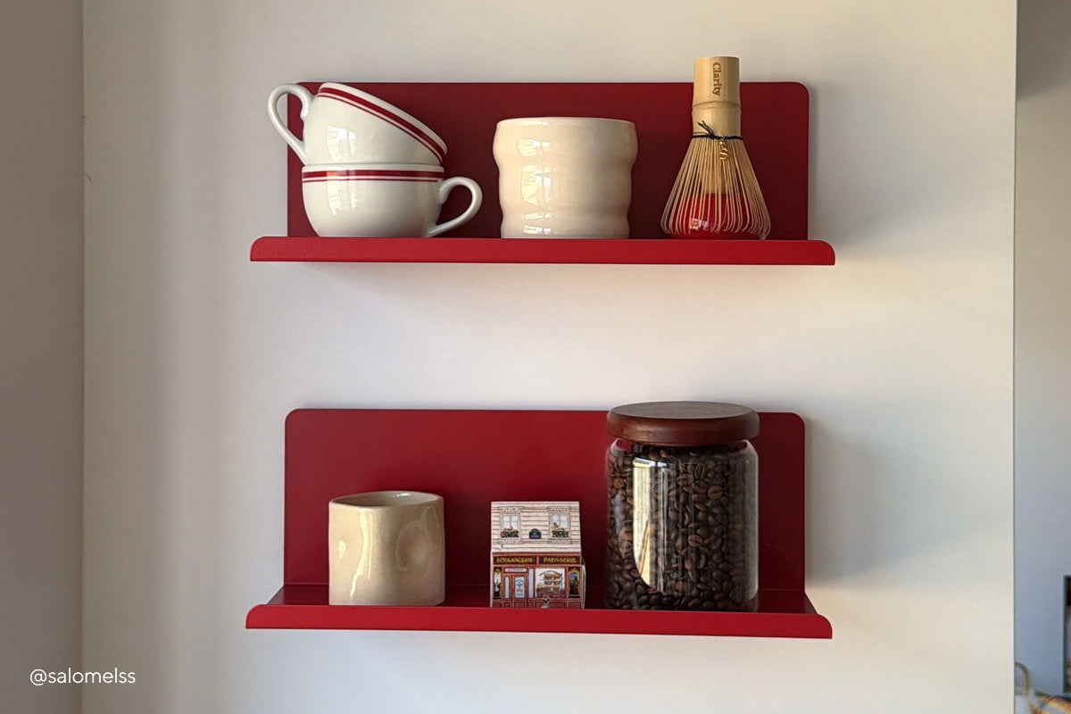 Un par de estantes Ledge «The Ledge » en rojo Poppy, dispuestos a modo de rincón de café con tazas, un batidor de matcha y un tarro de granos de café.