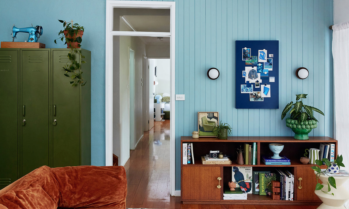 Un salón con paredes revestidas de paneles en tono «Ocean blue», tres armarios « Skinny » en color «Olive» y un tablón de anuncios «Navy» Storyboard , decorado con una paleta de colores 60-30-10.