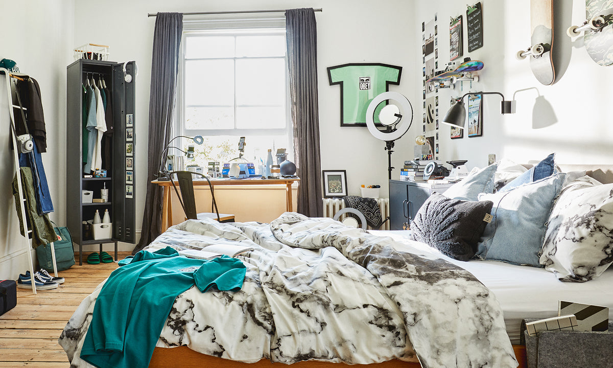 The Skinny locker in Slate, open as a wardrobe in a share house bedroom with a desk by the window and skateboards on the wall