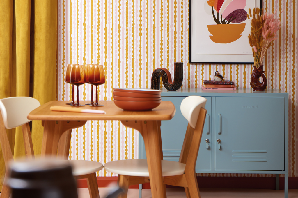 An Ocean Lowdown sits in a retro styled room against wallpaper with colourful, squiggly stripes.