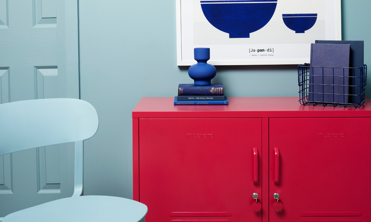 The Lowdown in Poppy against an Ocean blue wall.