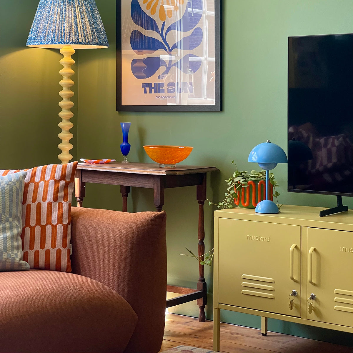 The Lowdown locker in Butter yellow used as a TV unit in a green living room