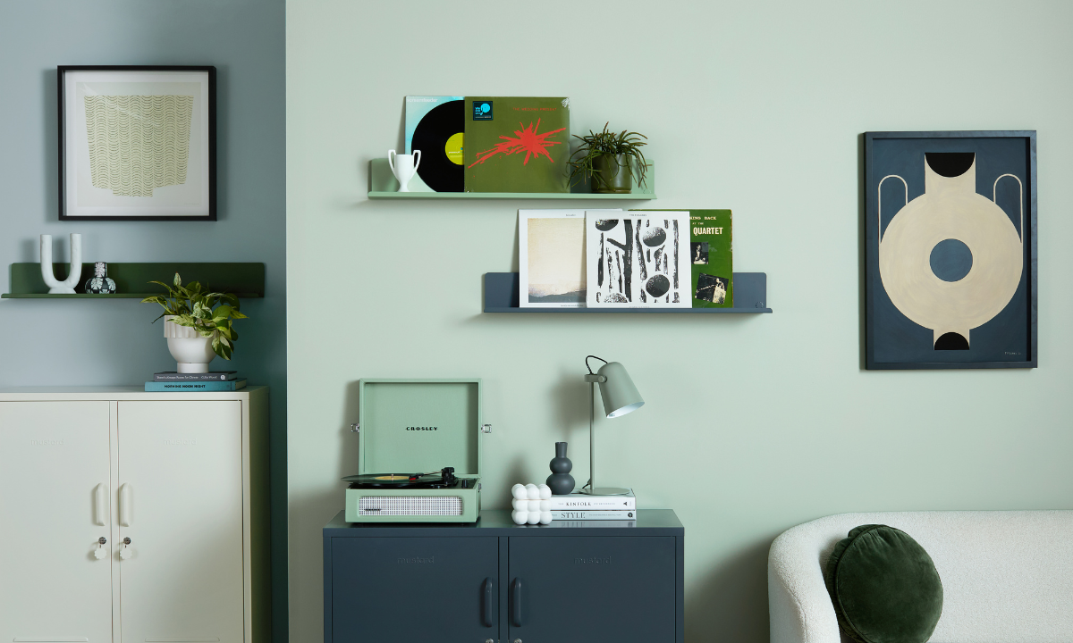 Ein Wohnzimmer, in dem The Lowdown in Slate und The Midi in Chalk vor einer salbeigrünen Wand stehen. Zwei Ledges hängen an der Wand, ebenso wie zwei Kunstwerke.