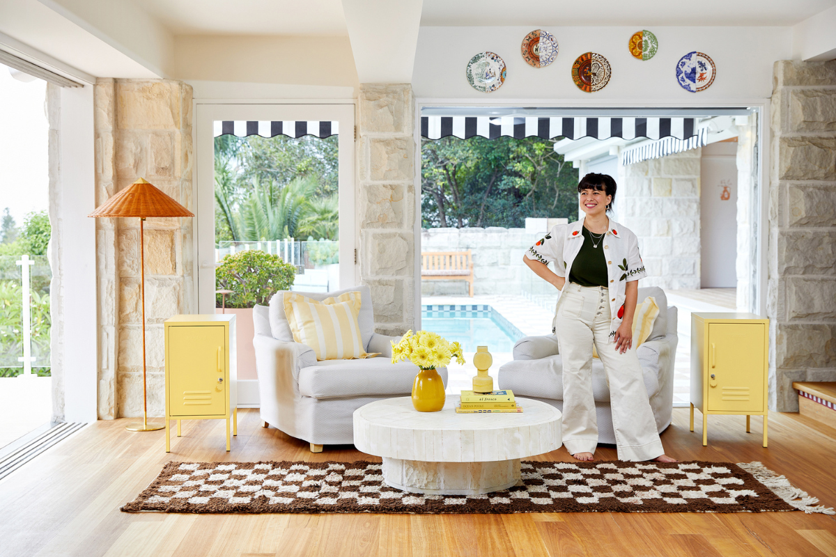 Becca está de pie en una casa muy bien decorada con dos Butter Shortys a cada lado. Al fondo se ve una piscina.