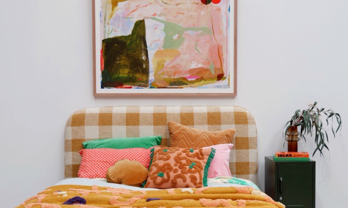 Des œuvres d'art colorées sont suspendues au-dessus d'un lit. Un casier Mustard Made se trouve à côté du lit.