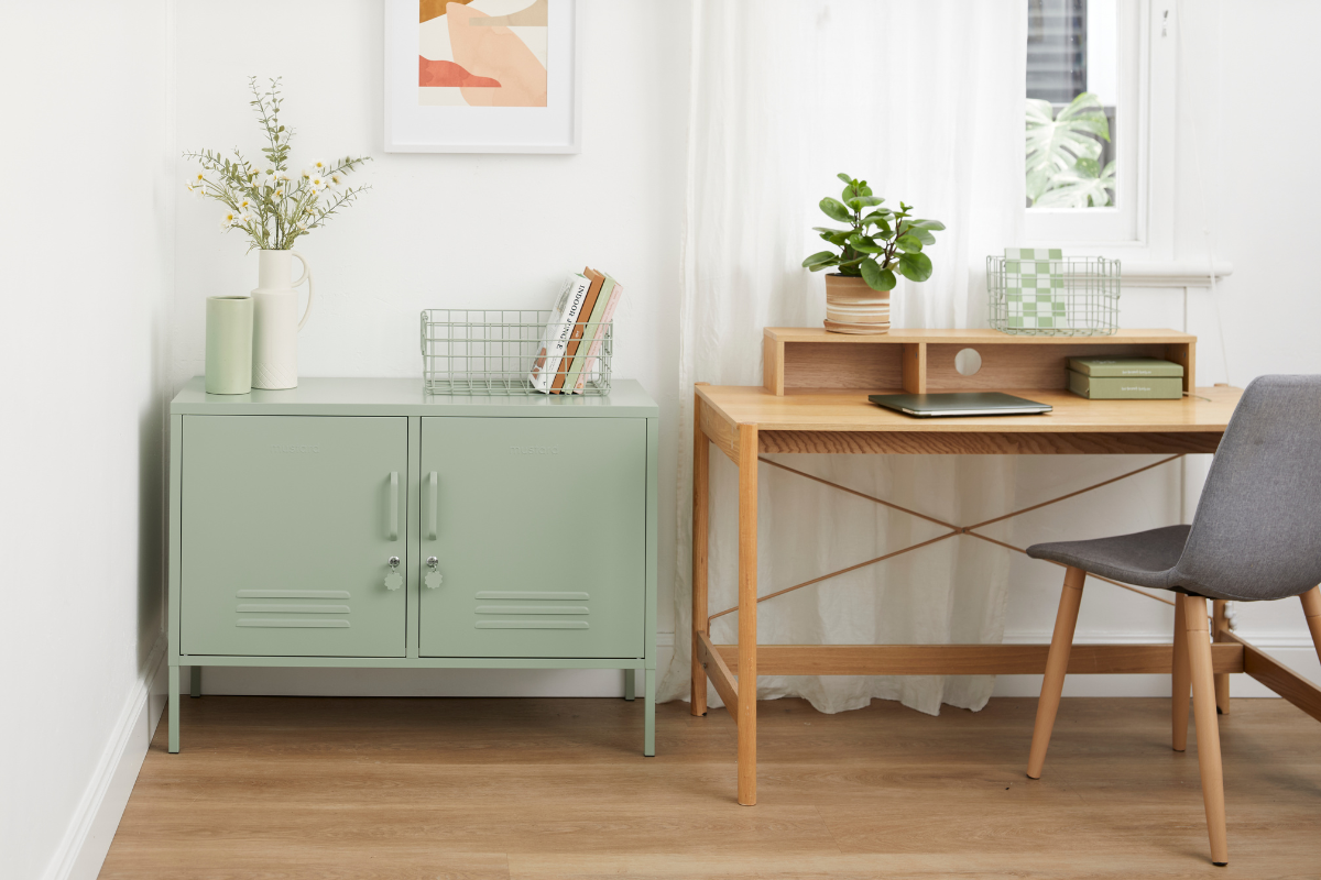 Un armadietto di Sage Lowdown si trova in un ufficio domestico accanto a una scrivania di legno con una sedia. Sulla scrivania c'è un computer portatile, mentre piccole piante in vaso e libri decorano lo spazio.